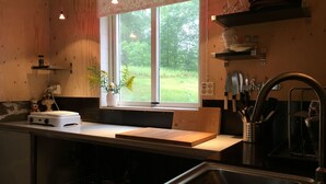 A kitchen with a window, wooden cabinets, a sink, and various kitchen utensils. - Lille Carlsson Studio (Broby)