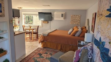 Une chambre à coucher avec un lit, un bureau, une chaise, une télévision et une fenêtre.