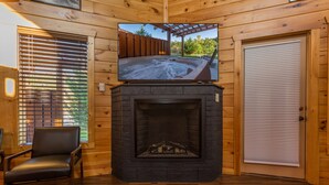 A wooden interior with a fireplace, a television mounted above it, and a door with a window. - The Game Changer! Next to Dollywood/Hot-Tub/Pool/LUXURY (Pigeon Forge)