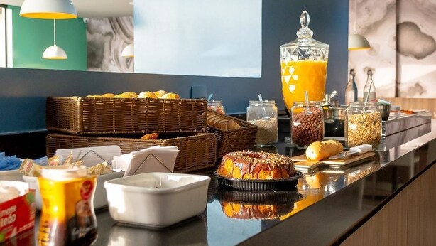 Un bufé de desayuno con diversas opciones de alimentos y un gran recipiente de vidrio con jugo de naranja.