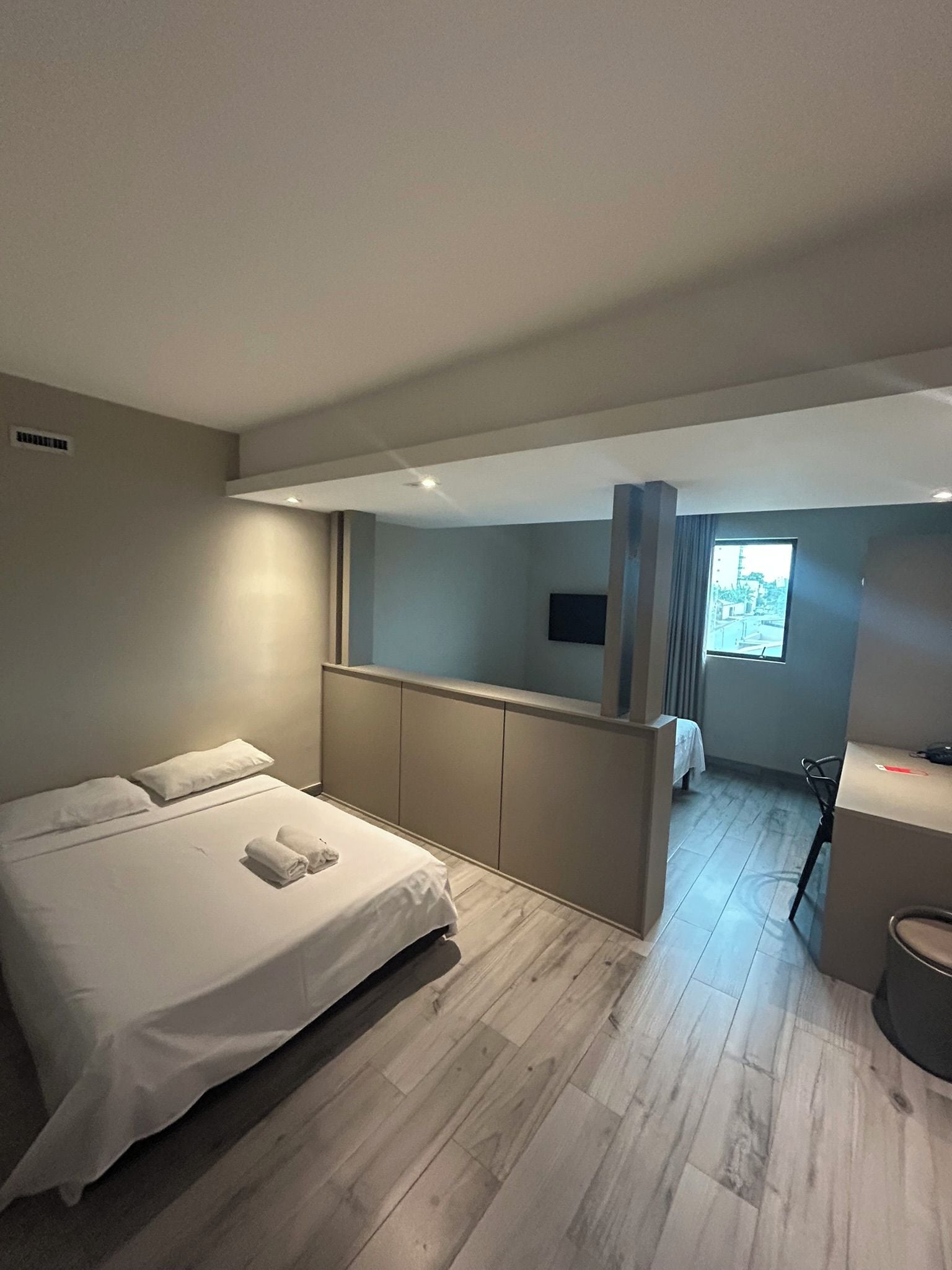 Un dormitorio moderno con cama, escritorio y vistas al exterior.