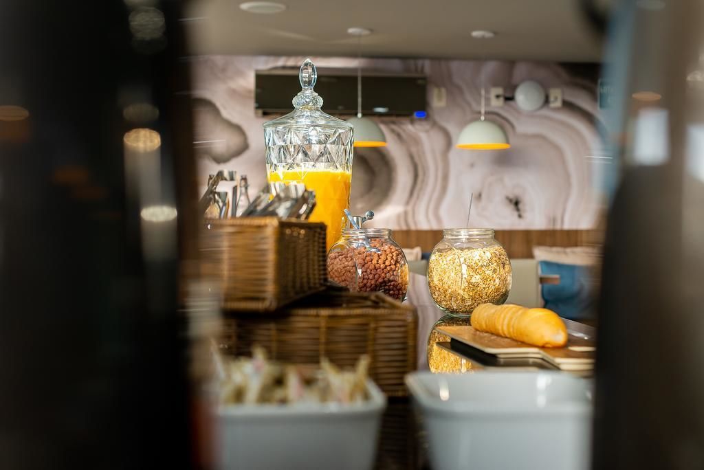 A breakfast buffet with various food items and a glass container of orange juice.