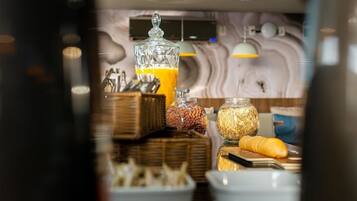 A breakfast buffet with various food items and a glass container of orange juice.