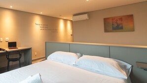 Una habitación de hotel con cama, escritorio, silla y una pared con una cita.