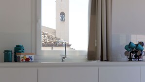 A kitchen with a window, a sink, and a view of a building outside. - Appartamento Agamennone (Ragusa)