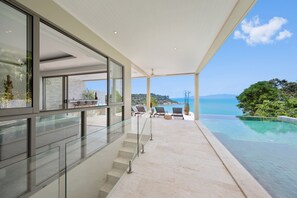 A modern outdoor area with a glass railing, a pool, and a view of the sea. - Samui Bayside Luxury Villas (Koh Samui)