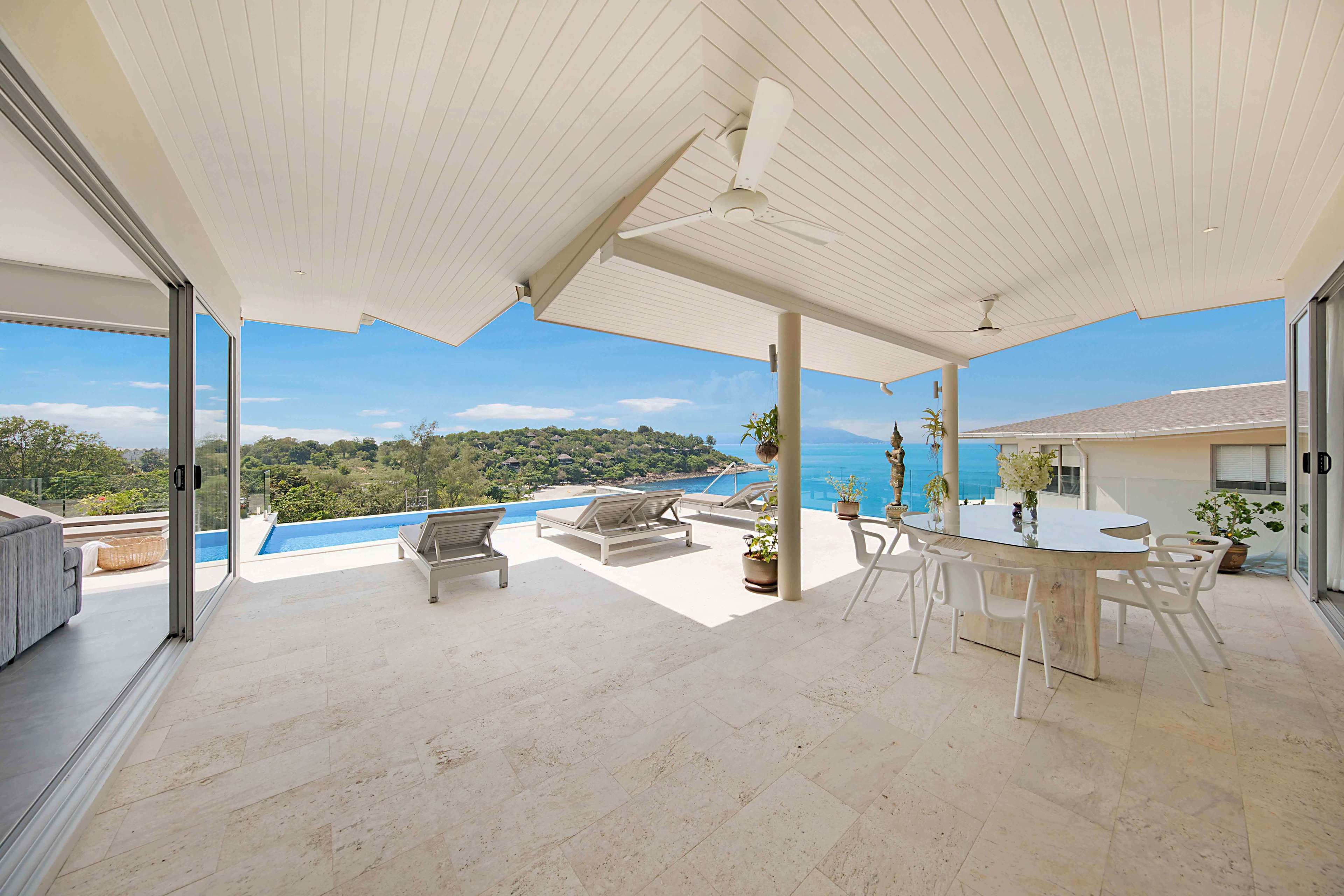 A spacious outdoor area with a pool, lounge chairs, and a dining table with chairs.