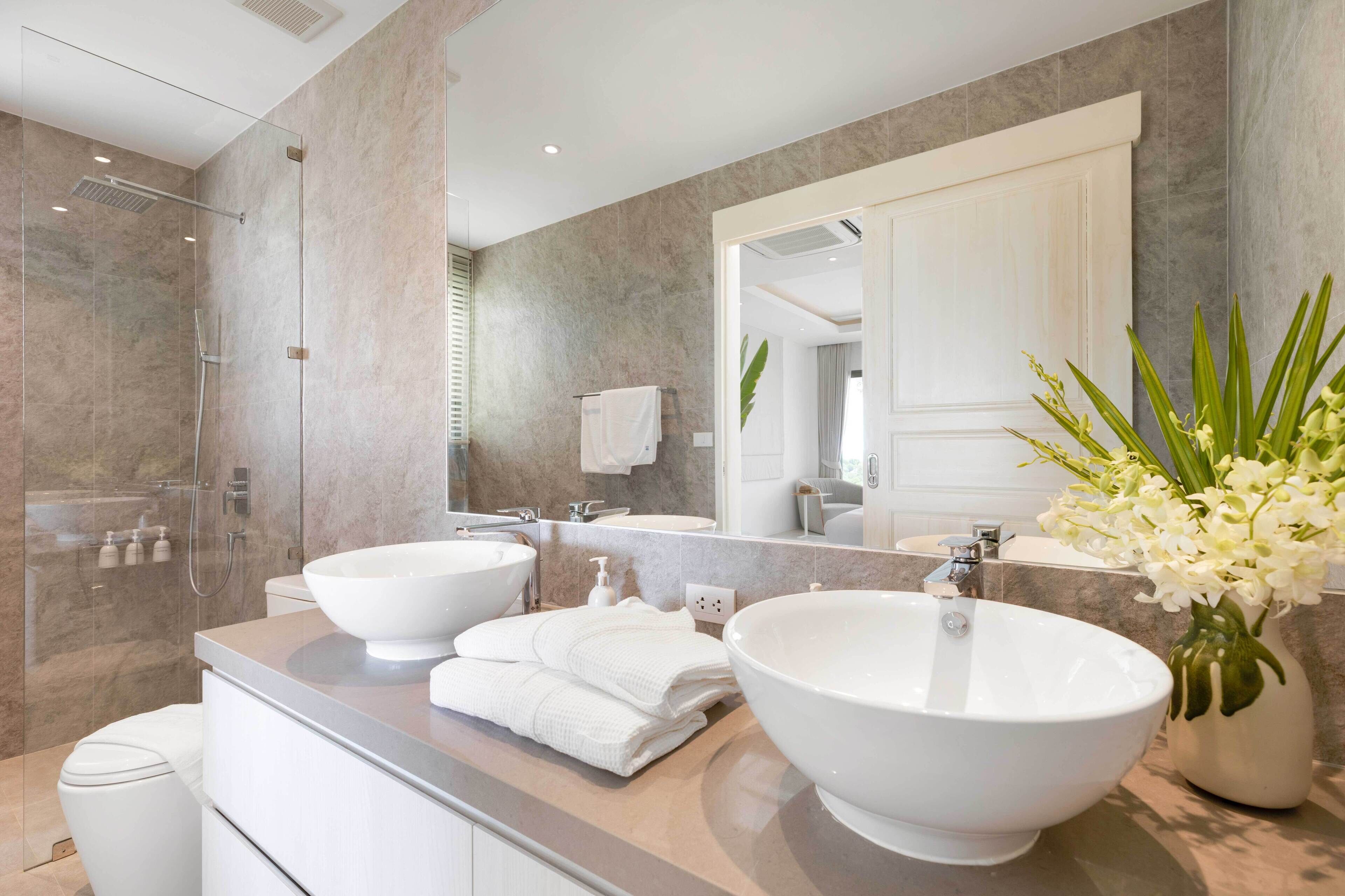 Ein modernes Badezimmer mit zwei Waschbecken, einer Dusche und einem großen Spiegel.