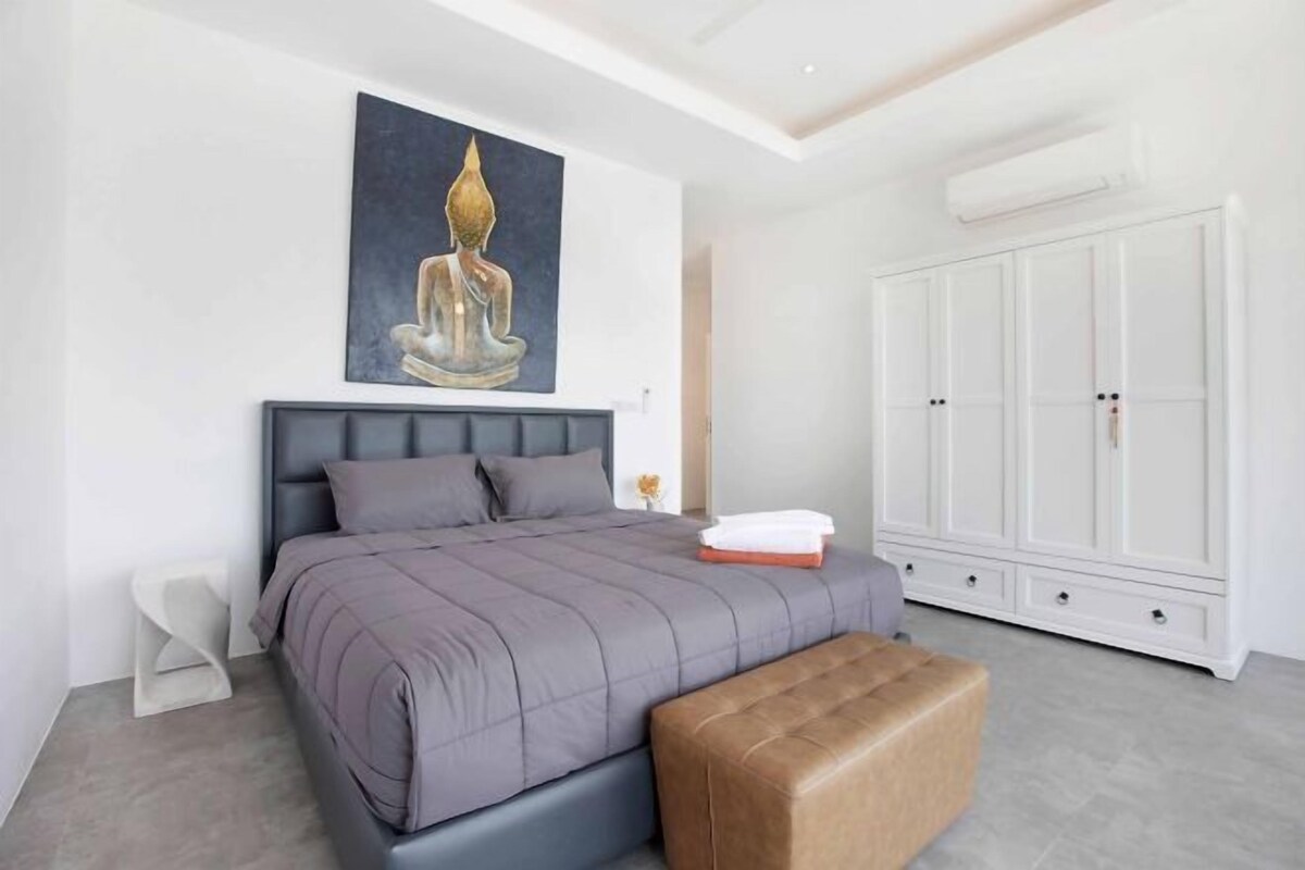 A bedroom with a bed, a bench, a wardrobe, and a painting on the wall.