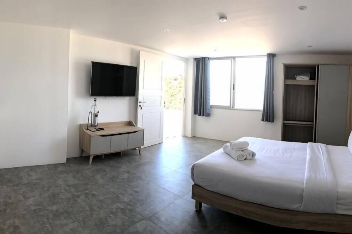 Una habitación de hotel moderna con cama, televisión, minibar y armario.
