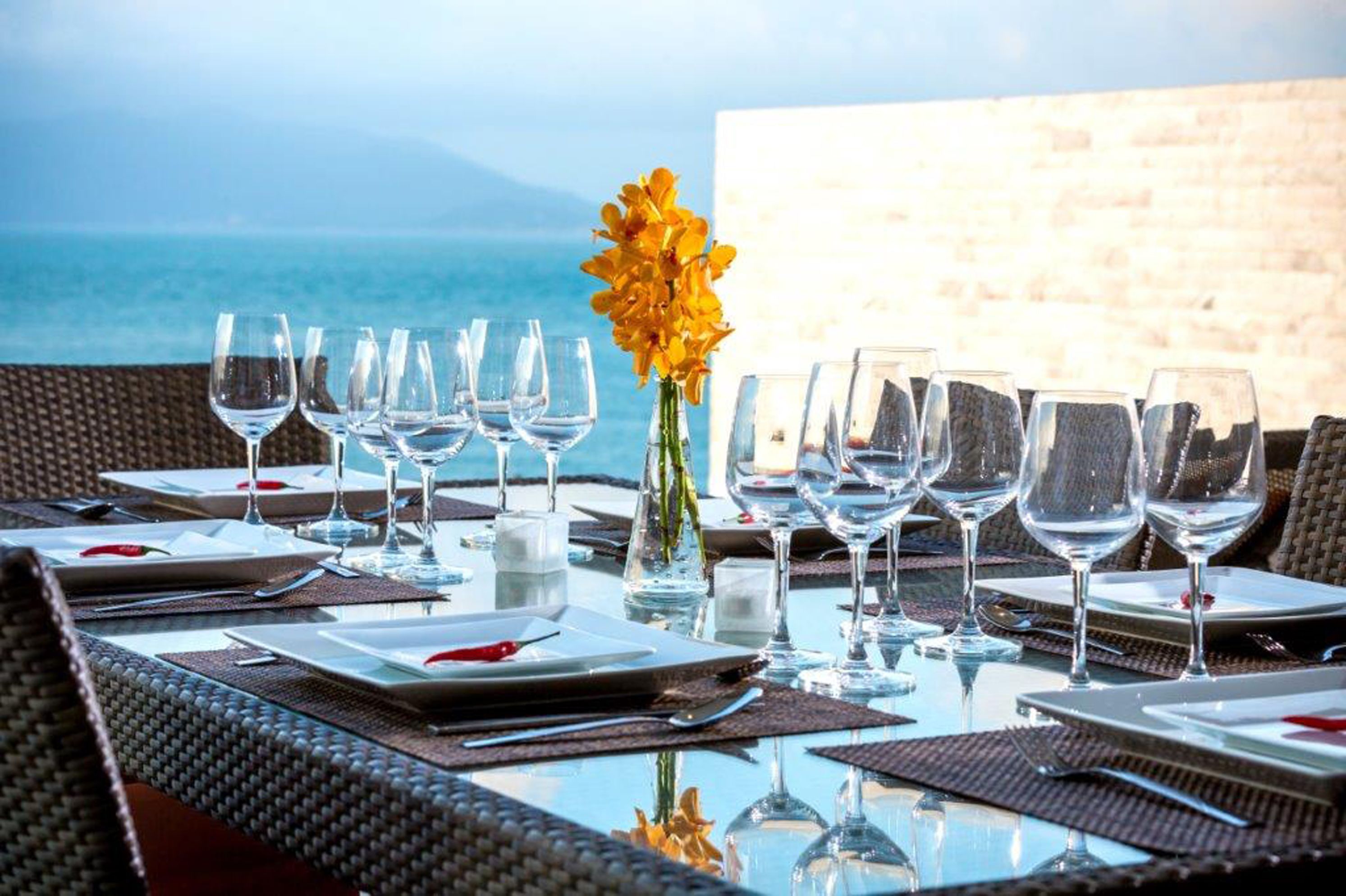 A table set for dining with a view of the sea and mountains.