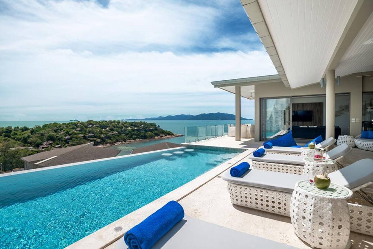 Zona de piscina con sillones de descanso y vista al mar.