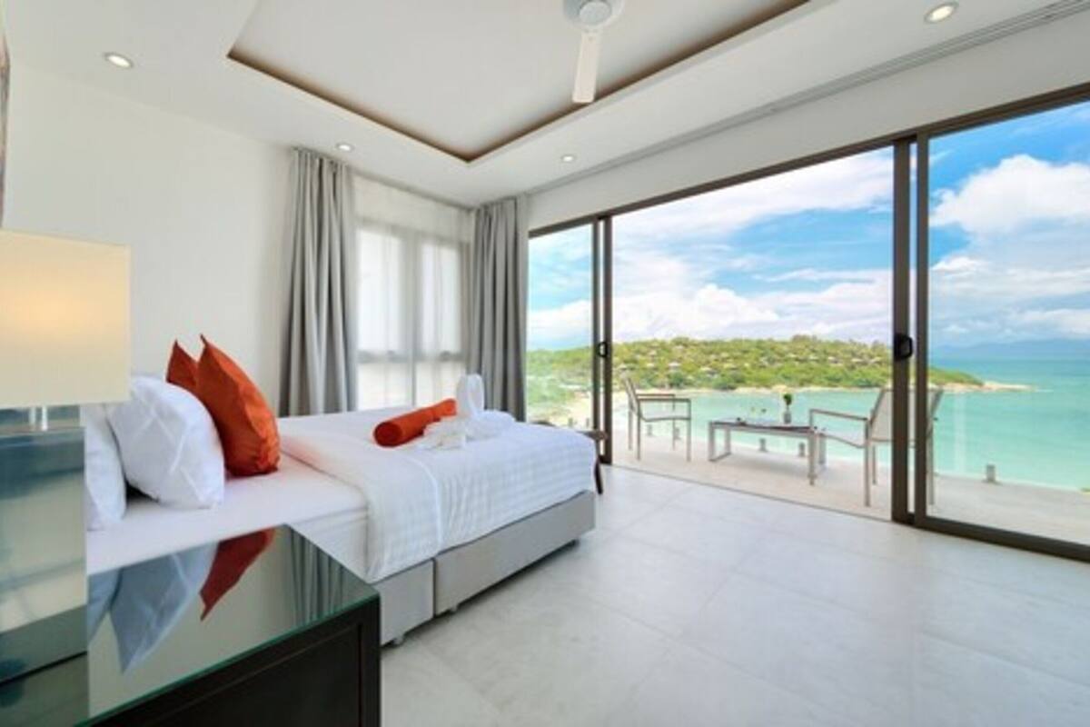 Una habitación de hotel moderna con una cama grande, un escritorio y un balcón con vista al mar.
