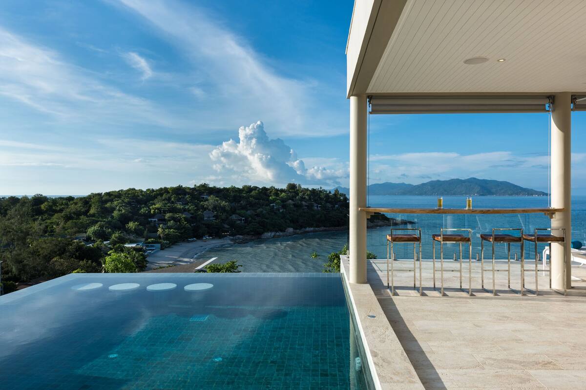 Una piscina infinita con vistas despejadas a una playa y montañas.