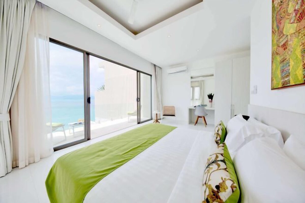 A hotel room with a large bed, a view of the sea, and a balcony.