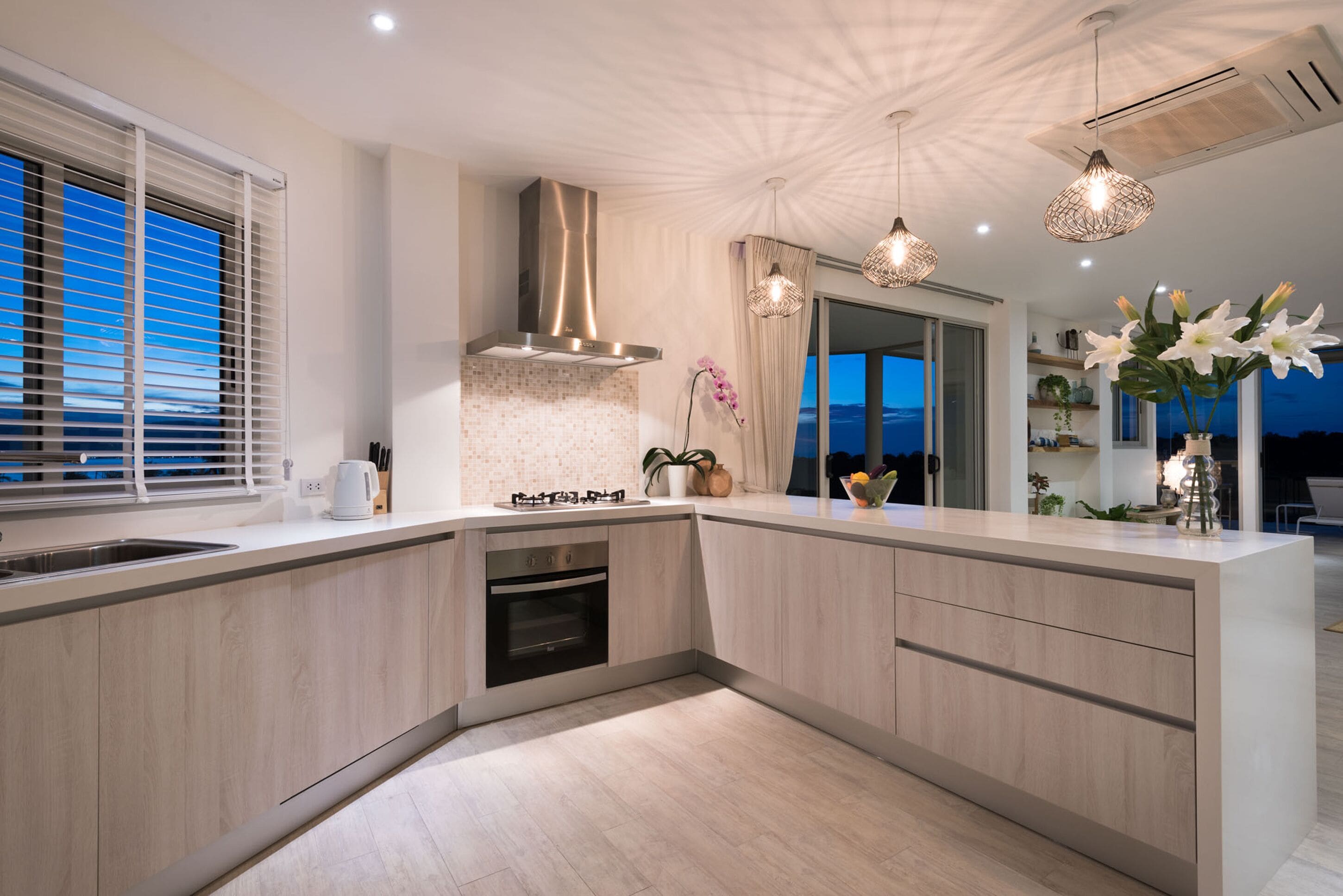 Una cocina moderna con una isla grande, electrodomésticos de acero inoxidable e iluminación colgante.