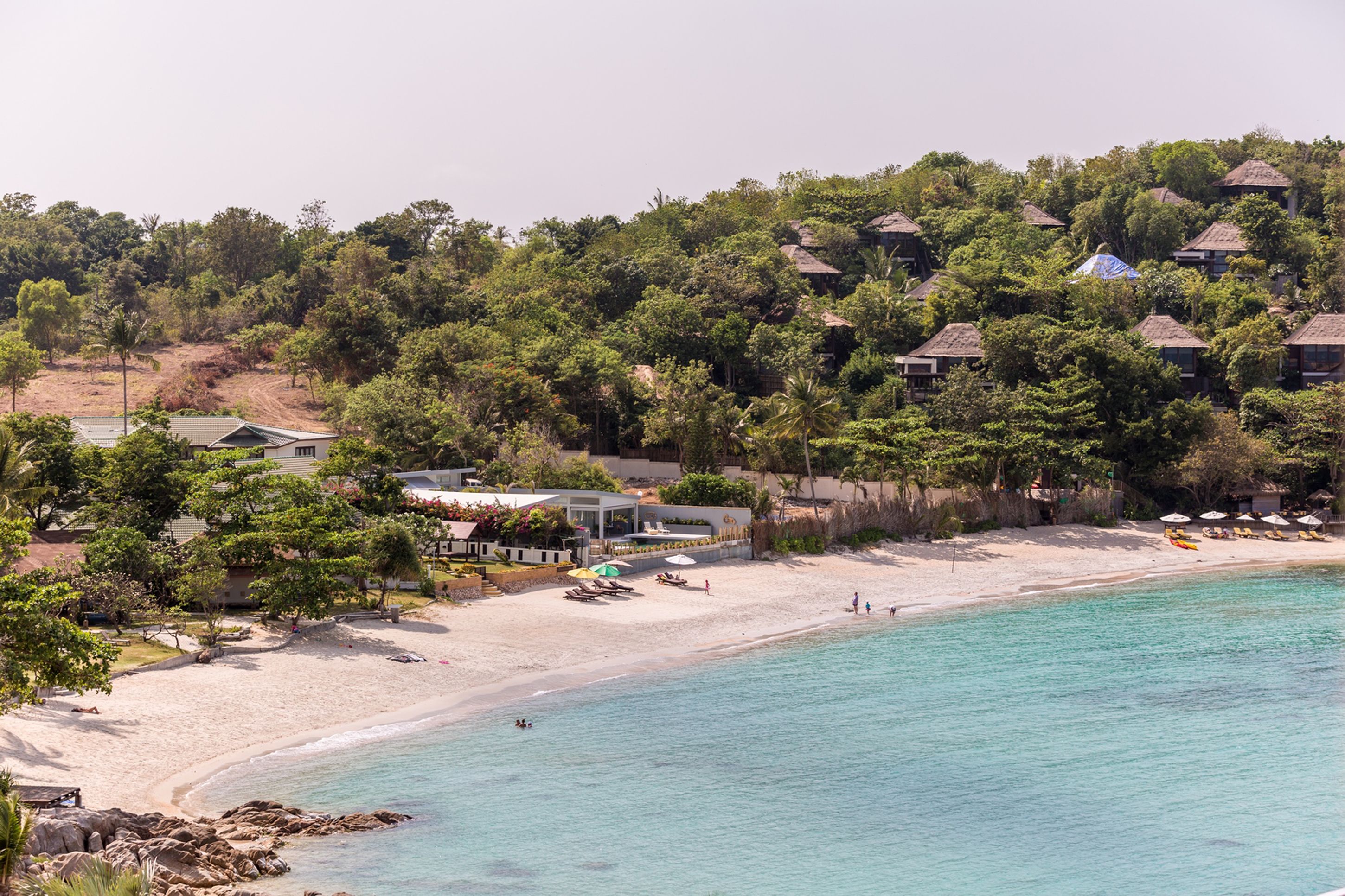 Ein Küstenresort mit Strandzugang, Bungalows über dem Wasser und einer Sandküste.