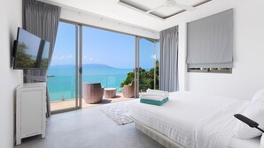Un dormitorio moderno con una cama grande, televisión y balcón con vista al mar.