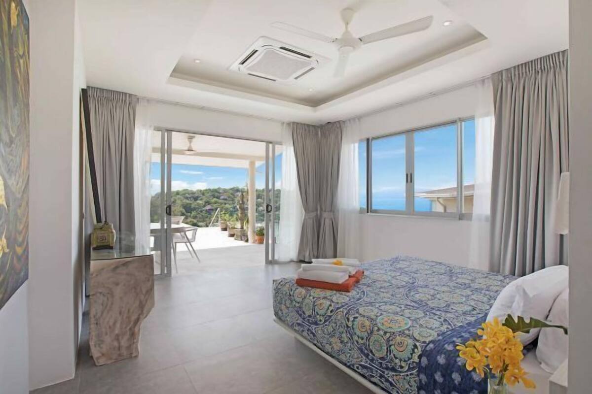 Una habitación de hotel moderna con una cama grande, un escritorio y un balcón con vistas.
