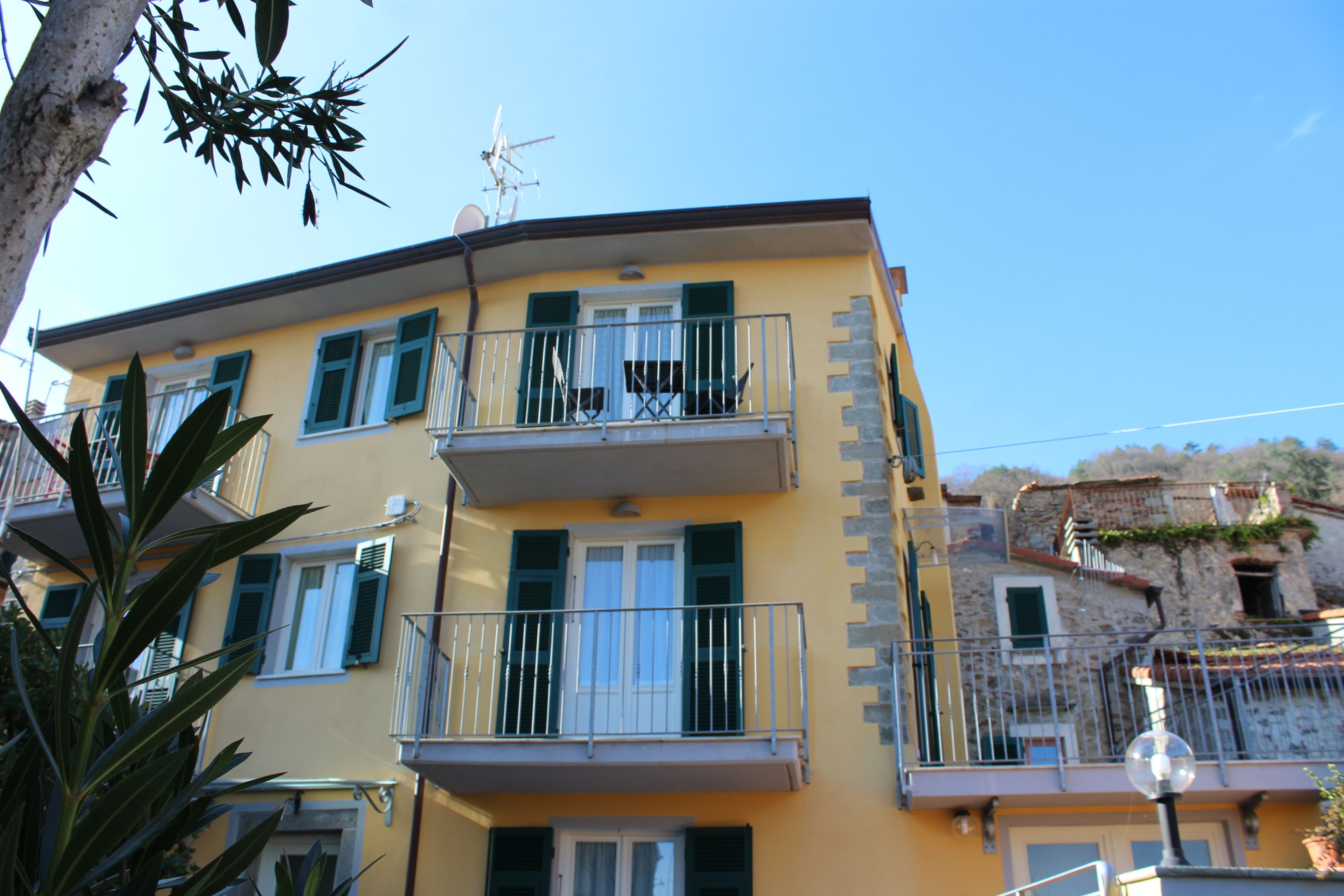Un immeuble jaune à plusieurs étages, doté de balcons, d’un escalier et d’un lampadaire.