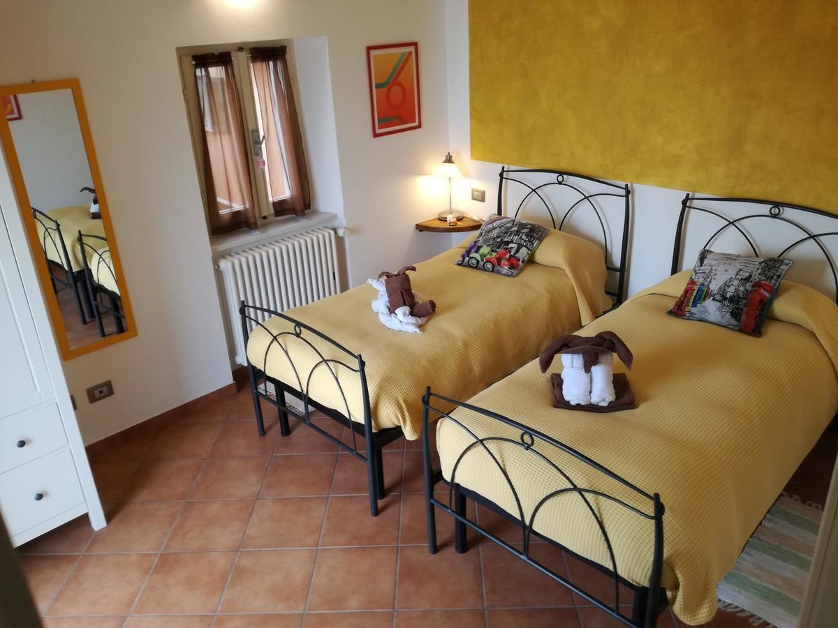Une chambre avec deux lits, un radiateur, un miroir, une table de chevet avec une lampe et une fenêtre avec des rideaux.