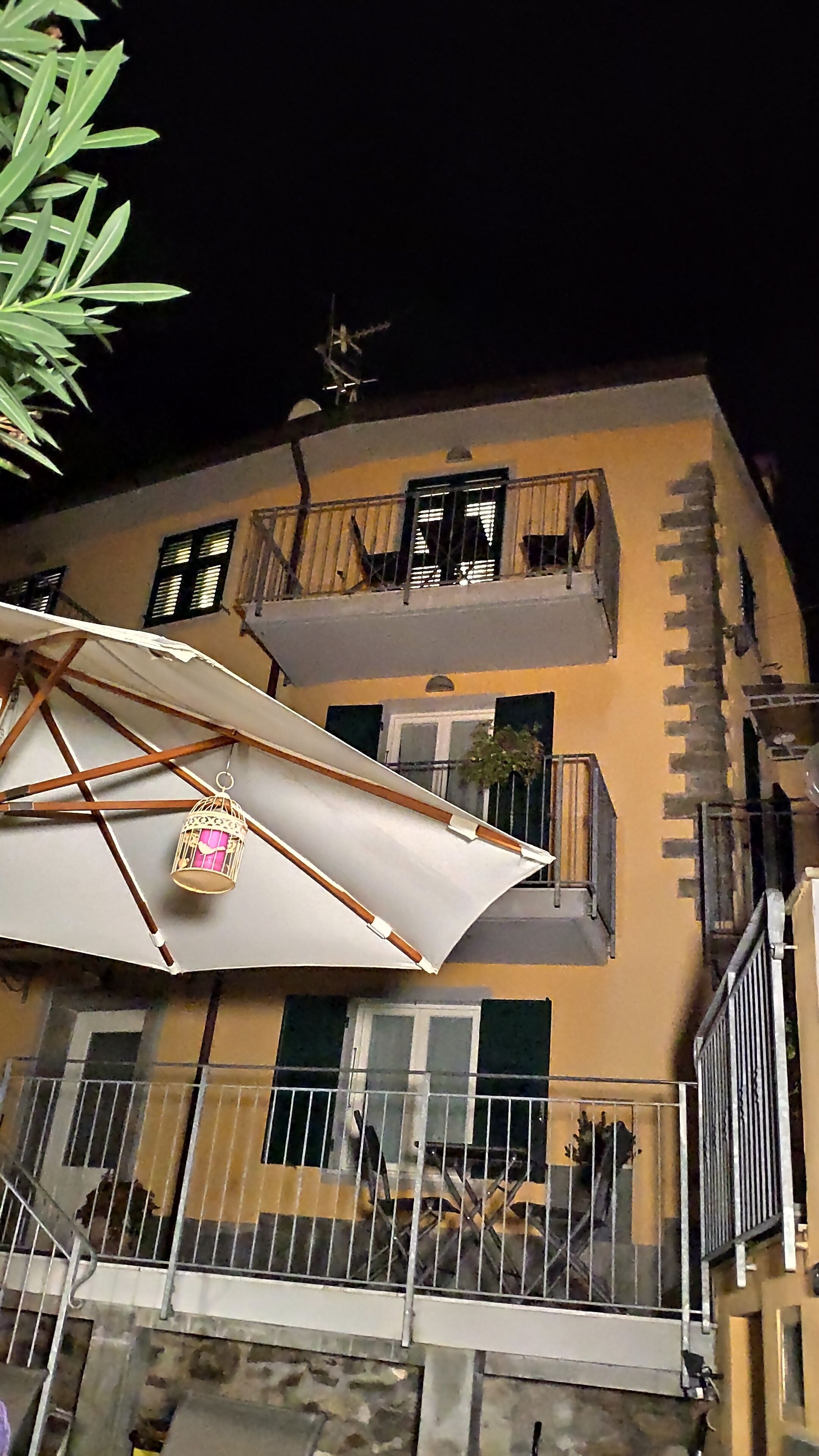 A multi-story building with balconies, a white umbrella, and a metal gate.