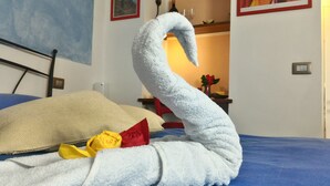 A bed with a swan-shaped towel and two roses. - Pietra Di Mare Guest House (La Spezia)