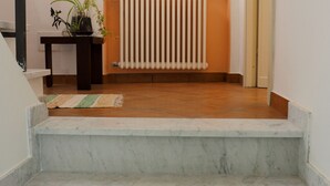 A staircase with marble steps leading to a landing. There is a radiator below the windows and a small table with a plant on the landing. - Pietra Di Mare Guest House (La Spezia)