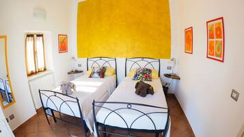 A room with two beds, a radiator, a window with curtains, and artwork on the walls.