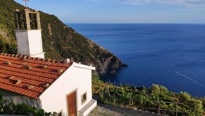 A coastal building with a red-tiled roof, a white facade, and a cross on top. - Pietra Di Mare Guest House (La Spezia)