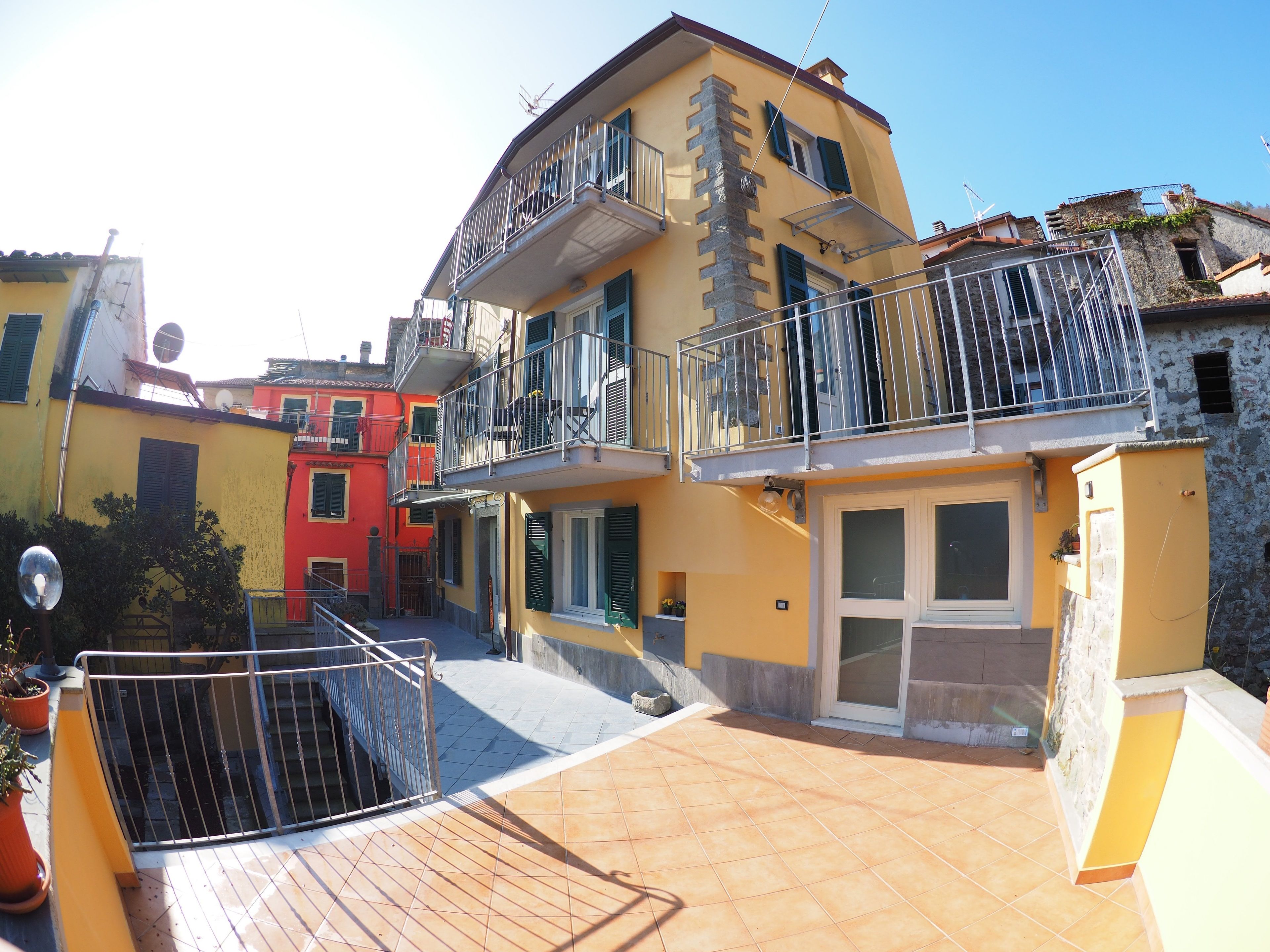 Un edificio de varios pisos con balcones, un patio empedrado y una mezcla de estilos arquitectónicos.