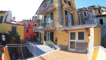 Un edificio de varios pisos con balcones, un patio empedrado y una mezcla de estilos arquitectónicos.