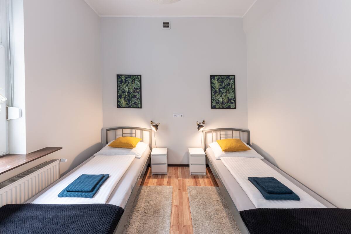 A twin room with two single beds, a small table, and a radiator.