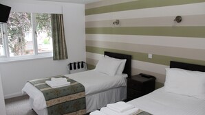 A hotel room with two beds, a window with curtains, a bedside table, and a wall-mounted light fixture. - Ravenswood Country Club Legion Scotland (Banchory)