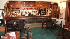 A bar area with wooden furniture, a counter with various bottles, and a green patterned carpet. - Ravenswood Country Club Legion Scotland (Banchory)