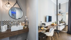 A modern bathroom with a large mirror, sink, and towel rack. The room has a wooden countertop and a black refrigerator. - Z-ArchSuiTes (Rome)
