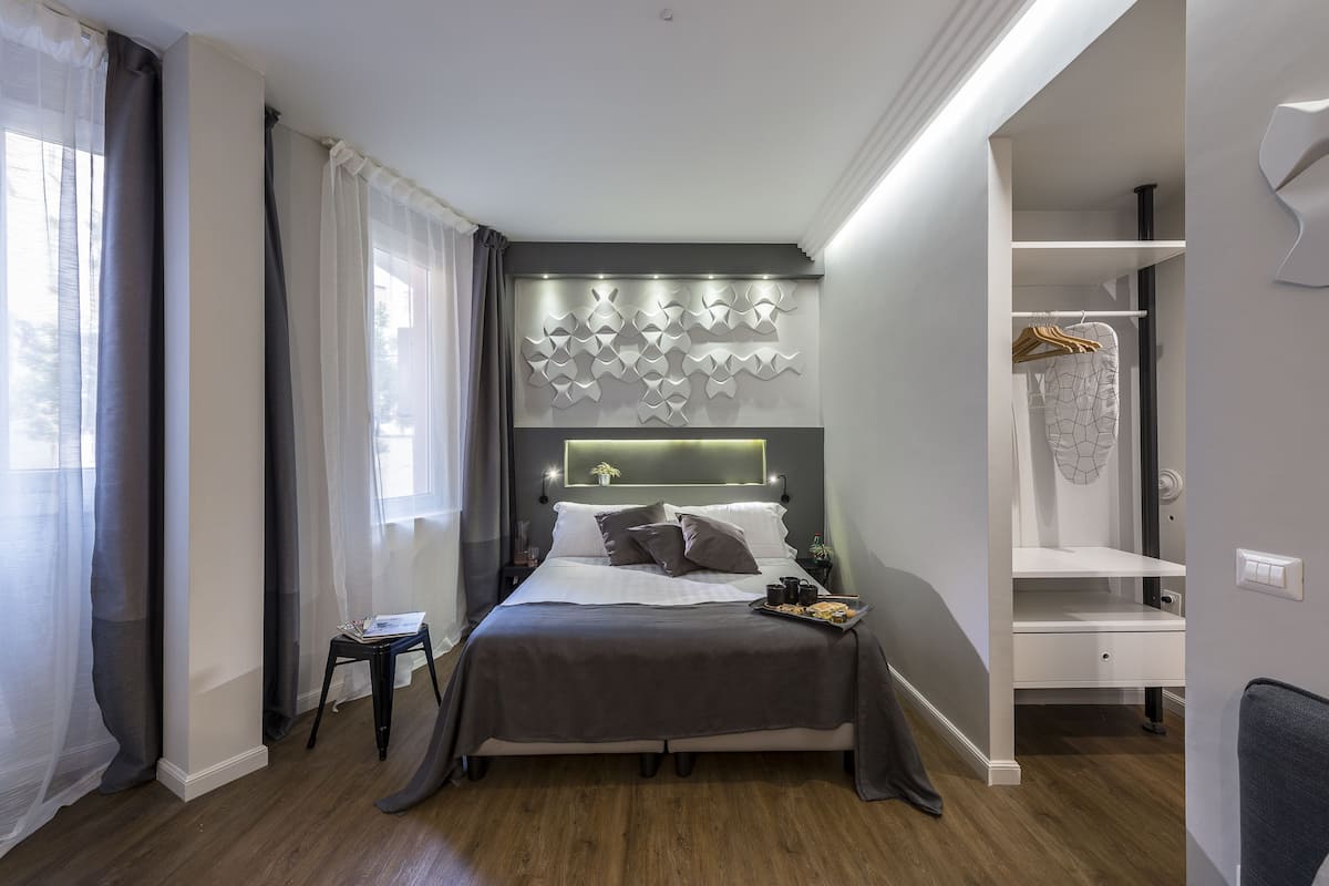 A modern bedroom with a bed, bedside tables, a dresser, and a closet.