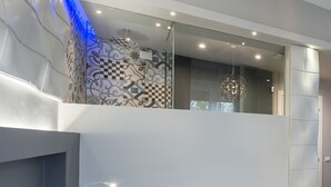 A modern bathroom with a checkered tile backsplash, a glass partition, and a pendant light. - Z-ArchSuiTes (Rome)