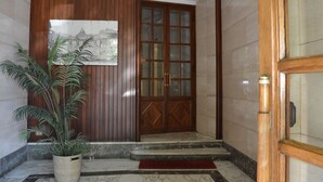 A wooden door with glass panels, a potted plant, and a marble floor. - Z-ArchSuiTes (Rome)