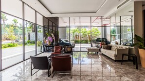 A modern lobby with a seating area, large windows, and a view of the street. - The Point Pratumnak by PSR ASIA (Pattaya)