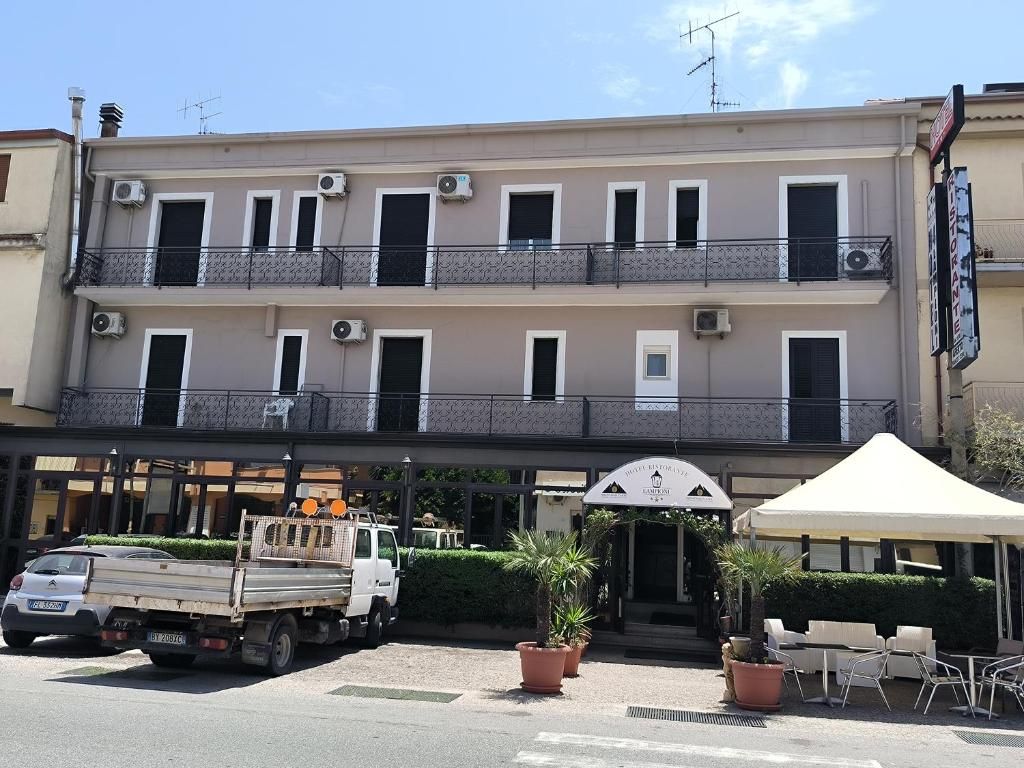 A multi-story hotel with balconies, a covered entrance, and outdoor seating.