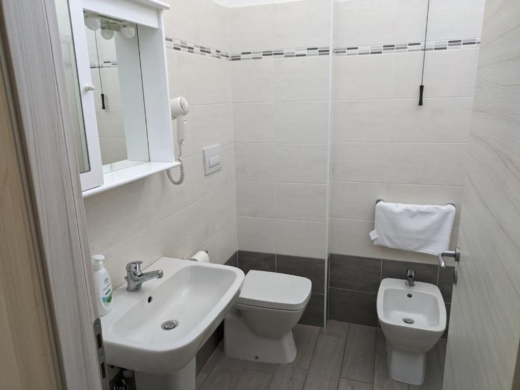 Un bagno con lavandino, WC, bidet e porta asciugamani.