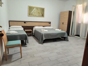 A hotel room with two beds, a wooden wardrobe, a chair, and a painting on the wall. - Hotel 4 Lampioni (Cropani)