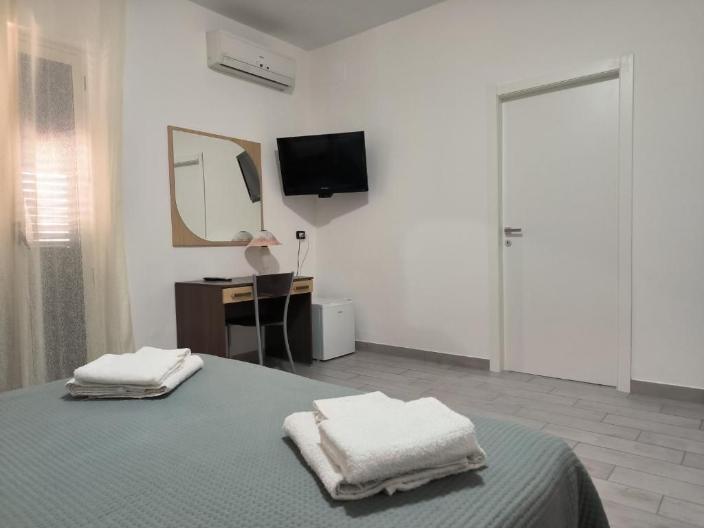 Habitación de hotel con una cama, un escritorio con una silla, un televisor y un equipo de aire acondicionado.