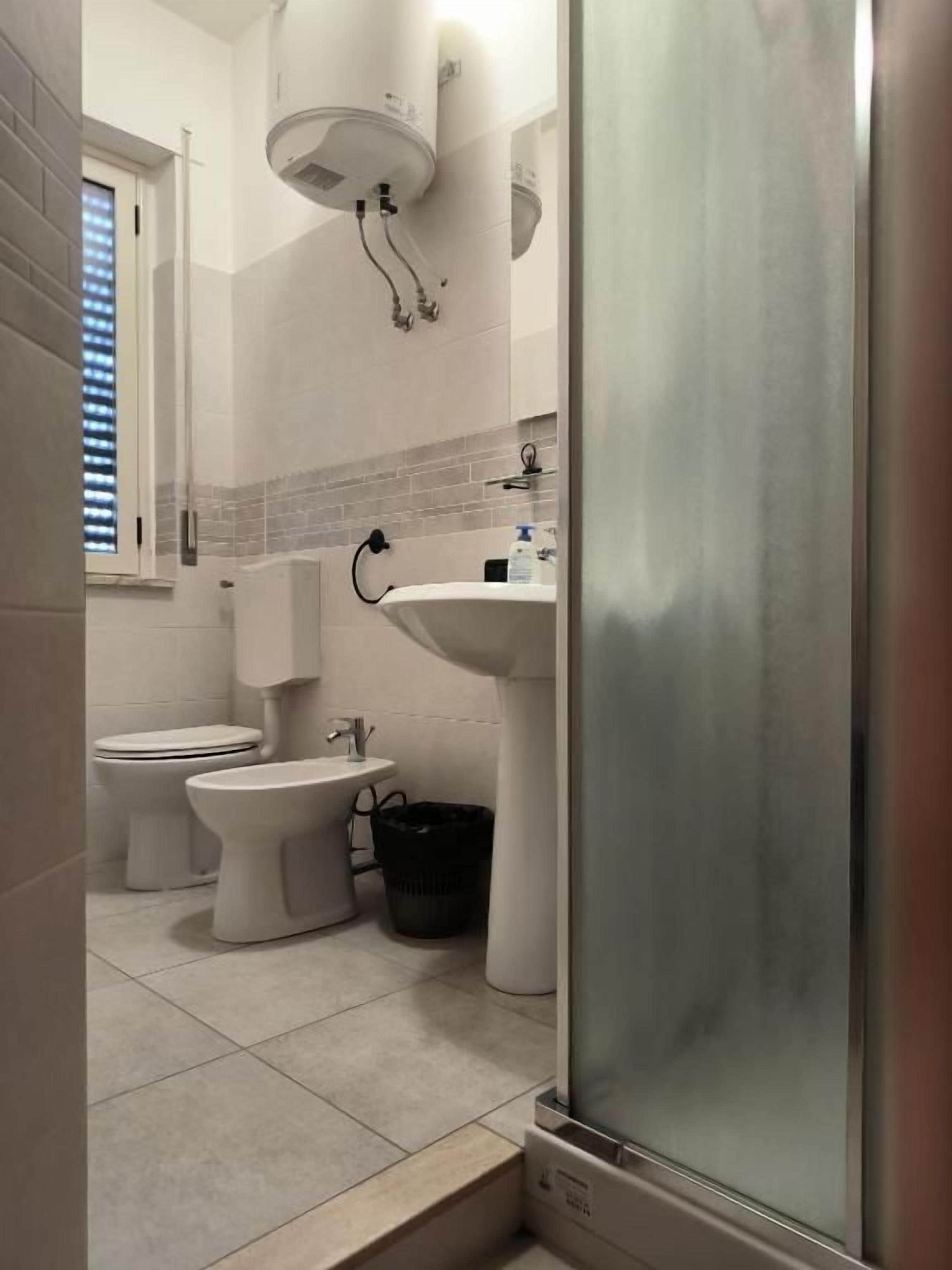 A bathroom with a shower, toilet, bidet, and sink.
