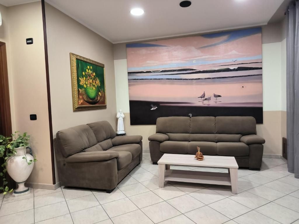 Un salon avec deux canapés, une table basse et un tableau accroché au mur.