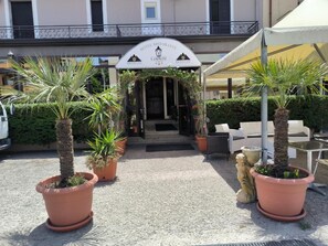 A hotel entrance with a sign reading 'HOTEL RESTORANTE LAMPIONI.' There are potted plants and outdoor seating visible. - Hotel 4 Lampioni (Cropani)