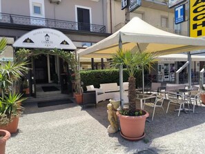 A hotel entrance with outdoor seating and a covered patio area. - Hotel 4 Lampioni (Cropani)