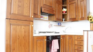 A kitchen with wooden cabinets, a stove, and an oven. - Art Apartment Bandinelli (Florence)