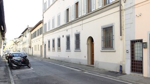 A street with parked cars and a building with multiple windows and doors. - Art Apartment Bandinelli (Florence)